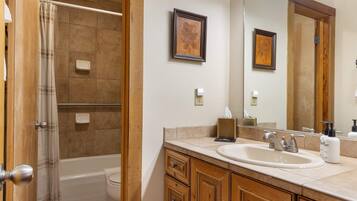 Une salle de bain avec une baignoire, un lavabo, des meubles en bois, un miroir et deux tableaux encadrés accrochés au mur.