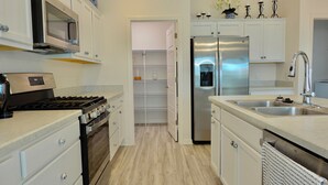 A modern kitchen with stainless steel appliances, white cabinetry, and a built-in oven. - Beautiful 3/2 Designer Home with Golf Cart & Dog Friendly – Village of Dabney (The Villages)