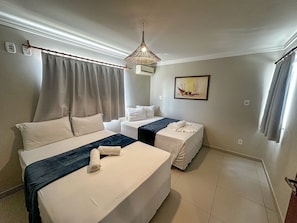 A hotel room with two beds, a painting on the wall, a ceiling light fixture, and a window with curtains. - Enseada Mutá (Porto Seguro)