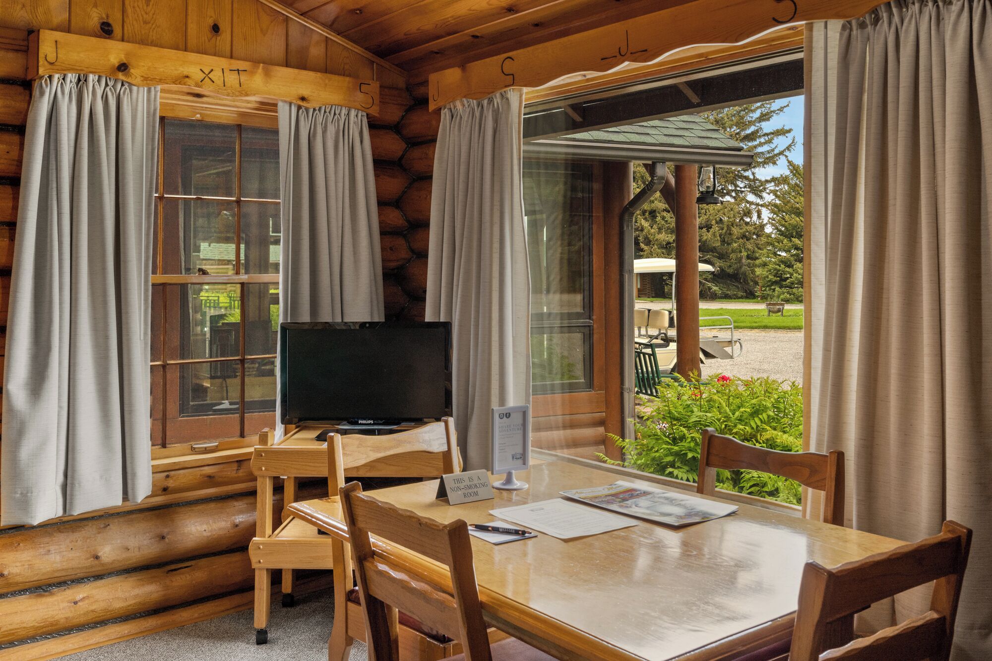 Ein Blockhausräume mit Fernseher, einem Tisch und Stühlen.