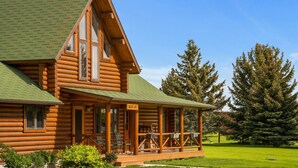 Une cabane en rondins dotée d’une véranda, de grandes fenêtres et d’une enseigne indiquant « Auberge de l  ’Aigle ».