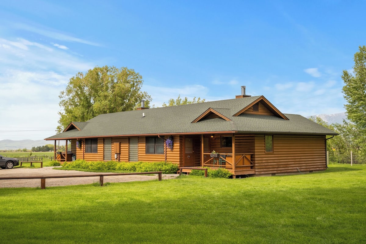 Eine Blockhütte mit Veranda, Schornstein und Blick auf die umliegende Landschaft.