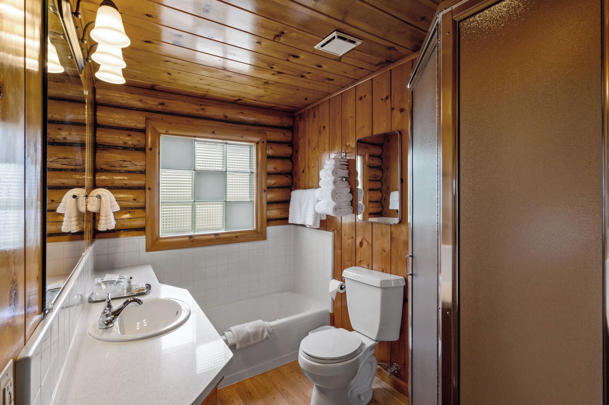 Bagno di una baita in legno con lavandino, WC e vasca da bagno.