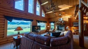 L'intérieur d'une cabane en rondins, avec une cheminée, un téléviseur et un canapé.