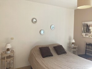 Ein Schlafzimmer mit einem Bett, zwei Nachttischen, einer Lampe und Wandspiegeln.