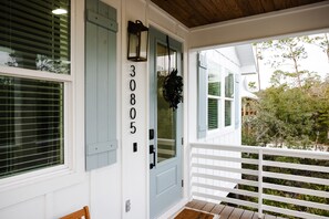 A house with a number 30805 on the door, a porch with a white railing, and a wooden deck. - Magnolia By The Bay – A charming 3-bedroom, 2-bath cottage in Perdido Beach, AL (Elberta)
