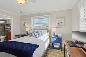 A bedroom with a bed, a desk with a computer, a window with blinds, and a ceiling fan. - Club Capri 101 (Treasure Island)