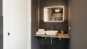 Ein modernes Badezimmer mit einem großen Spiegel, einem Händewaschbecken und einer Holzauslage.