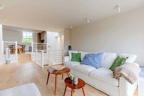 A modern living room with a white sofa, wooden coffee table, and a staircase leading to an upper level. - Chic 2BDR Maisonette with Private Terraces Chelsea (Greater London)