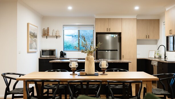 Une cuisine moderne avec une table à manger, des chaises, un réfrigérateur et une fenêtre.