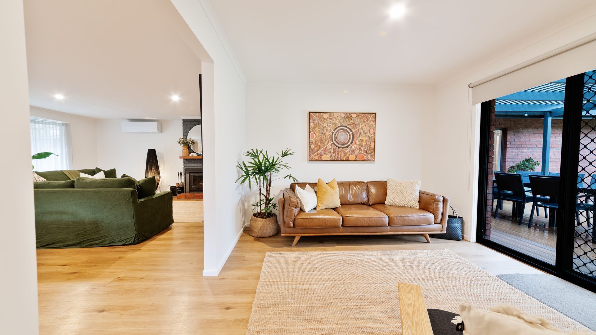 Un vaste espace de vie comprenant un canapé en cuir, un fauteuil vert et une grande fenêtre.
