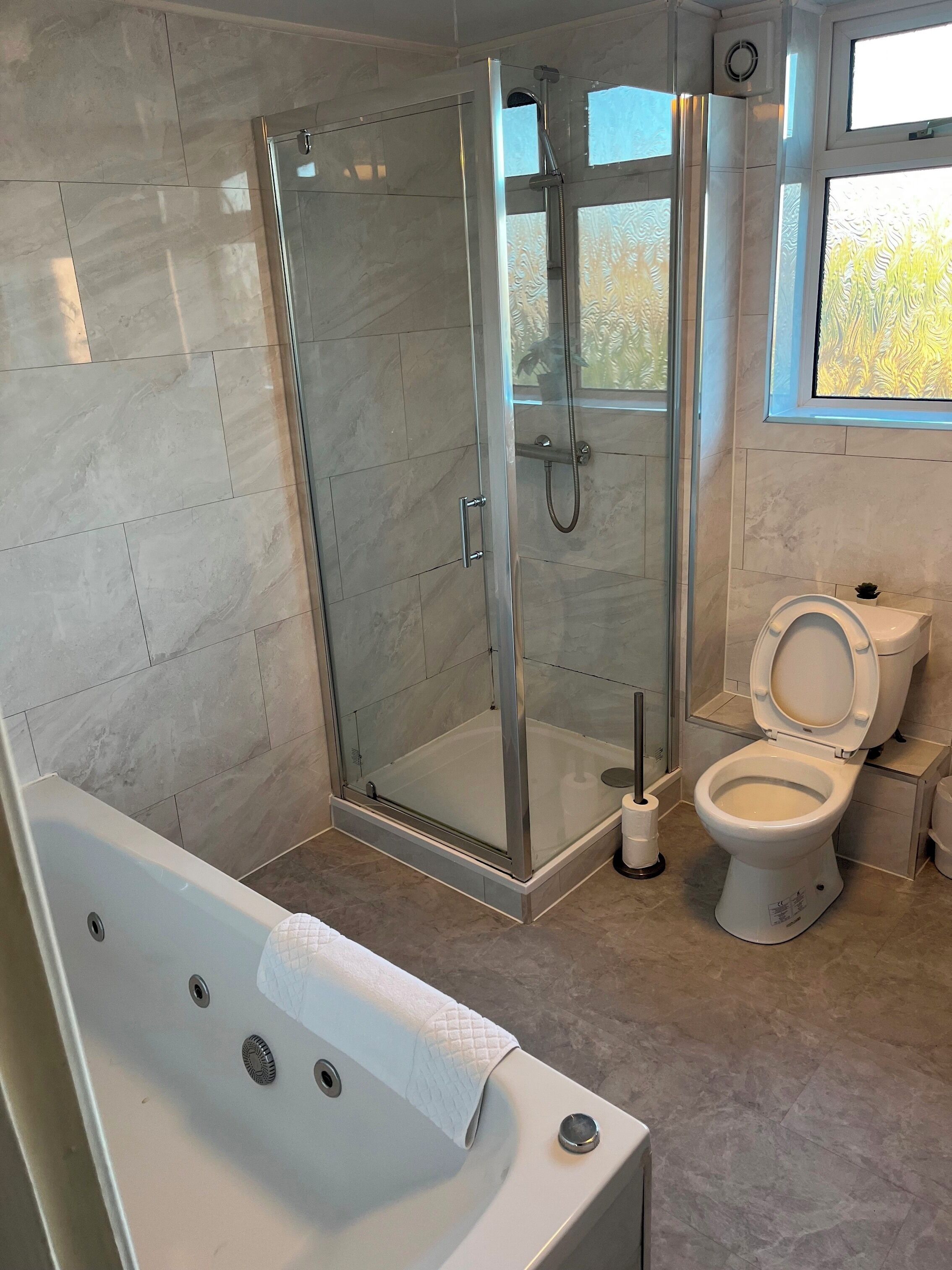 A modern bathroom with a glass-enclosed shower, a standalone bathtub, and a toilet.