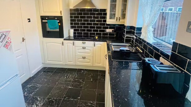 A kitchen with black and white tiled backsplash, white cabinets, and a stainless steel range hood. - Comfortable 2-Bed Flat in Heart of Tyne & Wear - Pass the Keys (North Shields)