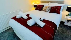 A neatly made bed with white and red bedding, a headboard, and a wall-mounted abstract painting. - Comfortable 2-Bed Flat in Heart of Tyne & Wear - Pass the Keys (North Shields)