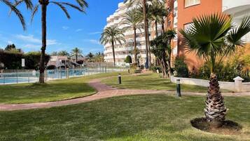 A resort with a pool, palm trees, and a well-maintained lawn.