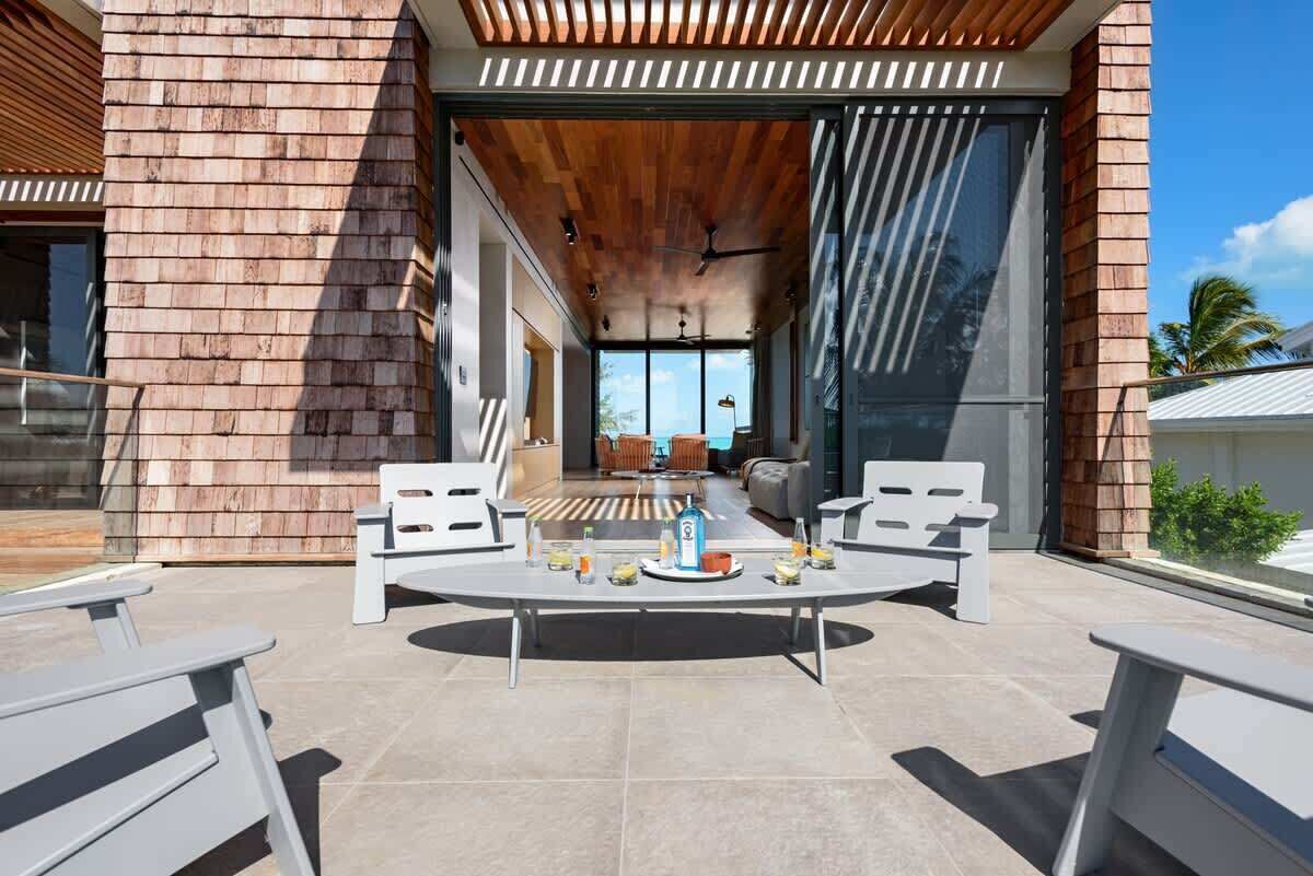 Eine Terrasse im Freien mit einem runden Tisch, zwei Stühlen, einer Holzbeschichtung und Blick ins Innere.