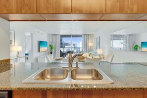 A modern kitchen with granite countertops, stainless steel sinks, and wooden cabinets. - Brickell Skyline Suite (Miami)
