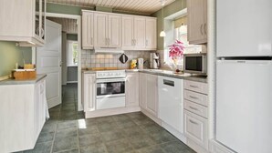 A kitchen with white cabinets, a stove, a microwave, and a refrigerator. - 4 Star Holiday Home in Hals (Hals)
