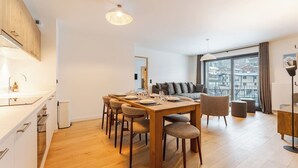 Een modern appartement met een eethoek, een bank en een groot raam met uitzicht op de stad.
