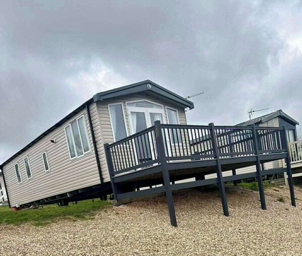 Ein Wohnmobil mit Balkon, einer Haustür und einer kleinen Veranda.