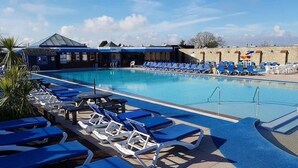 Una piscina con sillones de descanso y una zona cubierta.