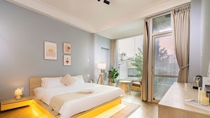 A modern hotel room with a bed, bedside table, lamp, and a view of the city through large windows. - Chill Hill Hotel & Home (Ho Chi Minh City)