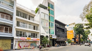 A multi-story building with various commercial establishments on the ground floor, including a restaurant and a shop with a prominent sign. - Chill Hill Hotel & Home (Ho Chi Minh City)