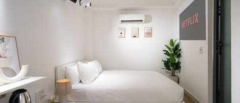 A modern bedroom with a bed, bedside lamp, air conditioning unit, and a wall-mounted Netflix sign.