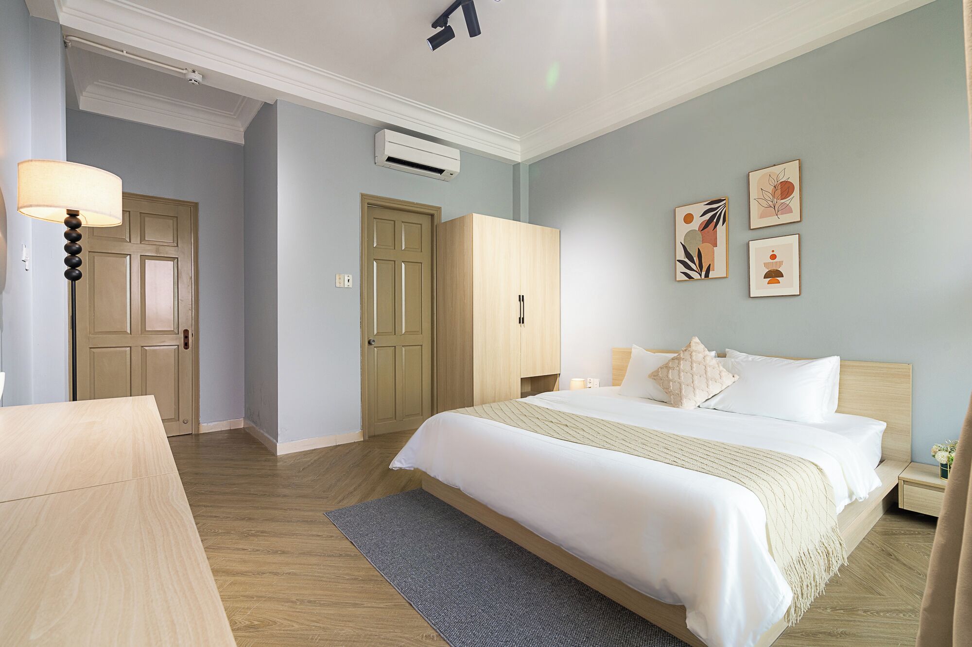 A hotel room with a bed, bedside tables, a wardrobe, and a desk.