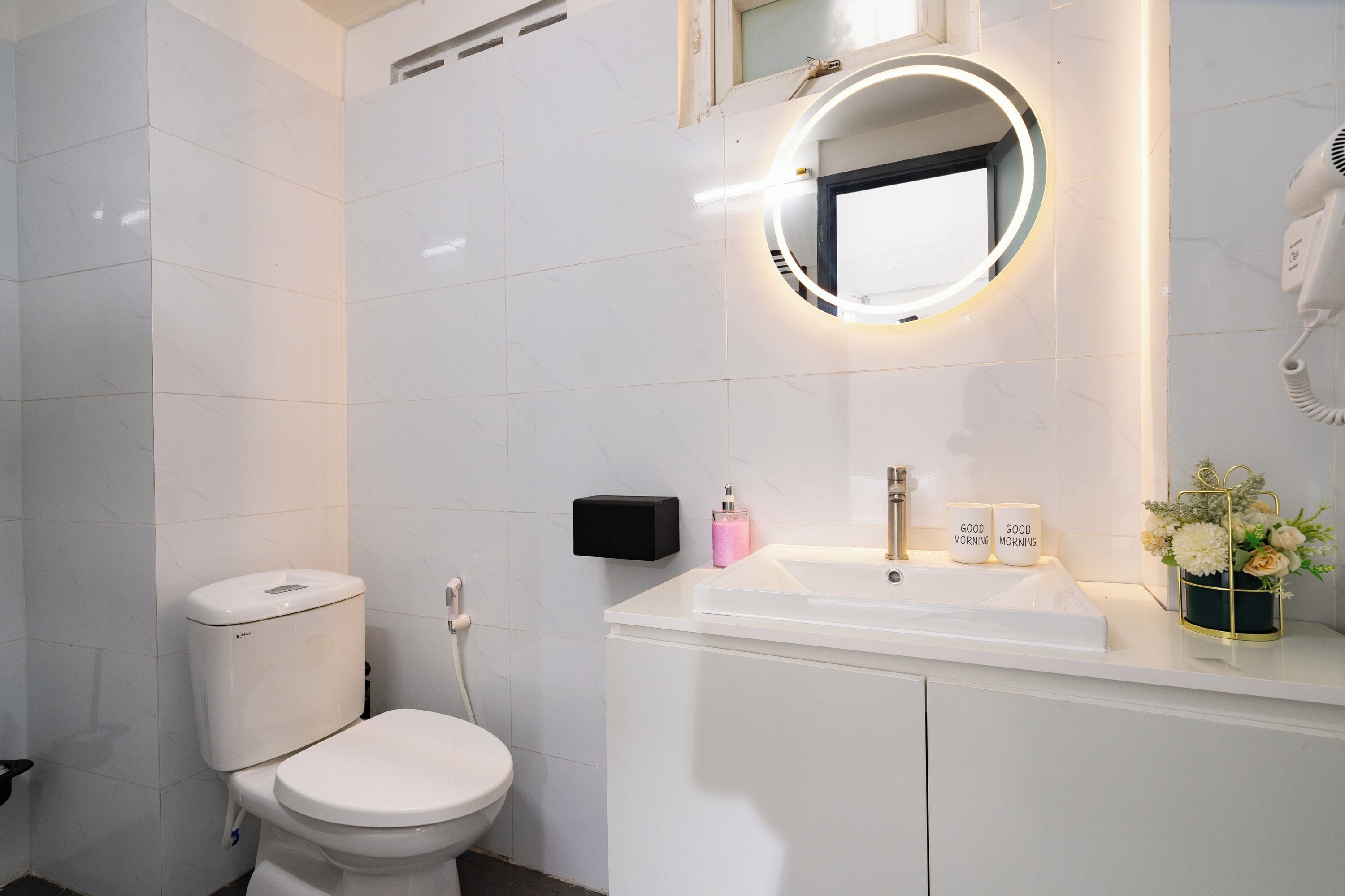 A modern bathroom with a toilet, sink, and a mirror with a light.
