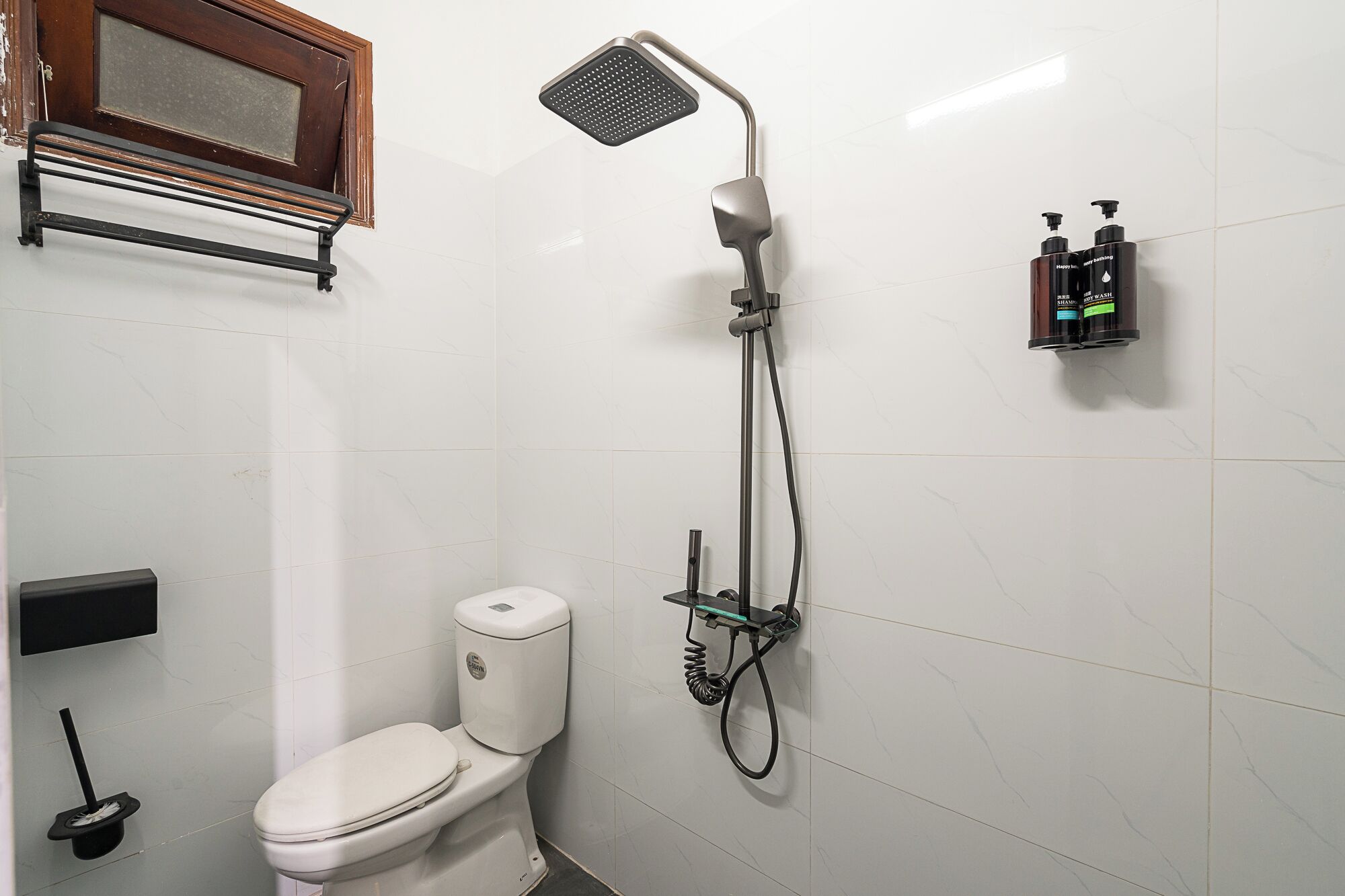 Ein Badezimmer mit Dusche, Toilette und Ablage für Toilettenartikel.