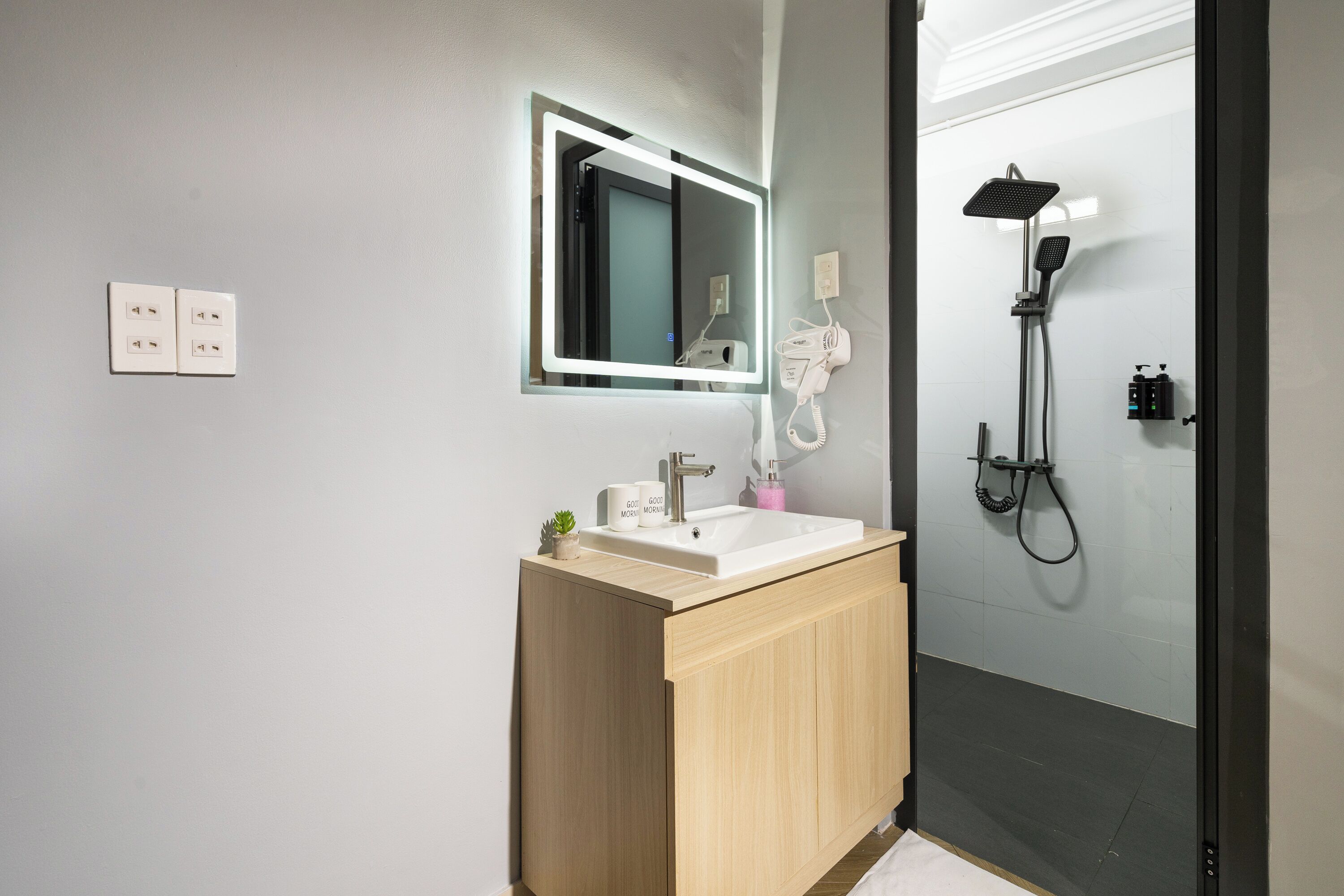 A modern bathroom with a sink, mirror, and shower.