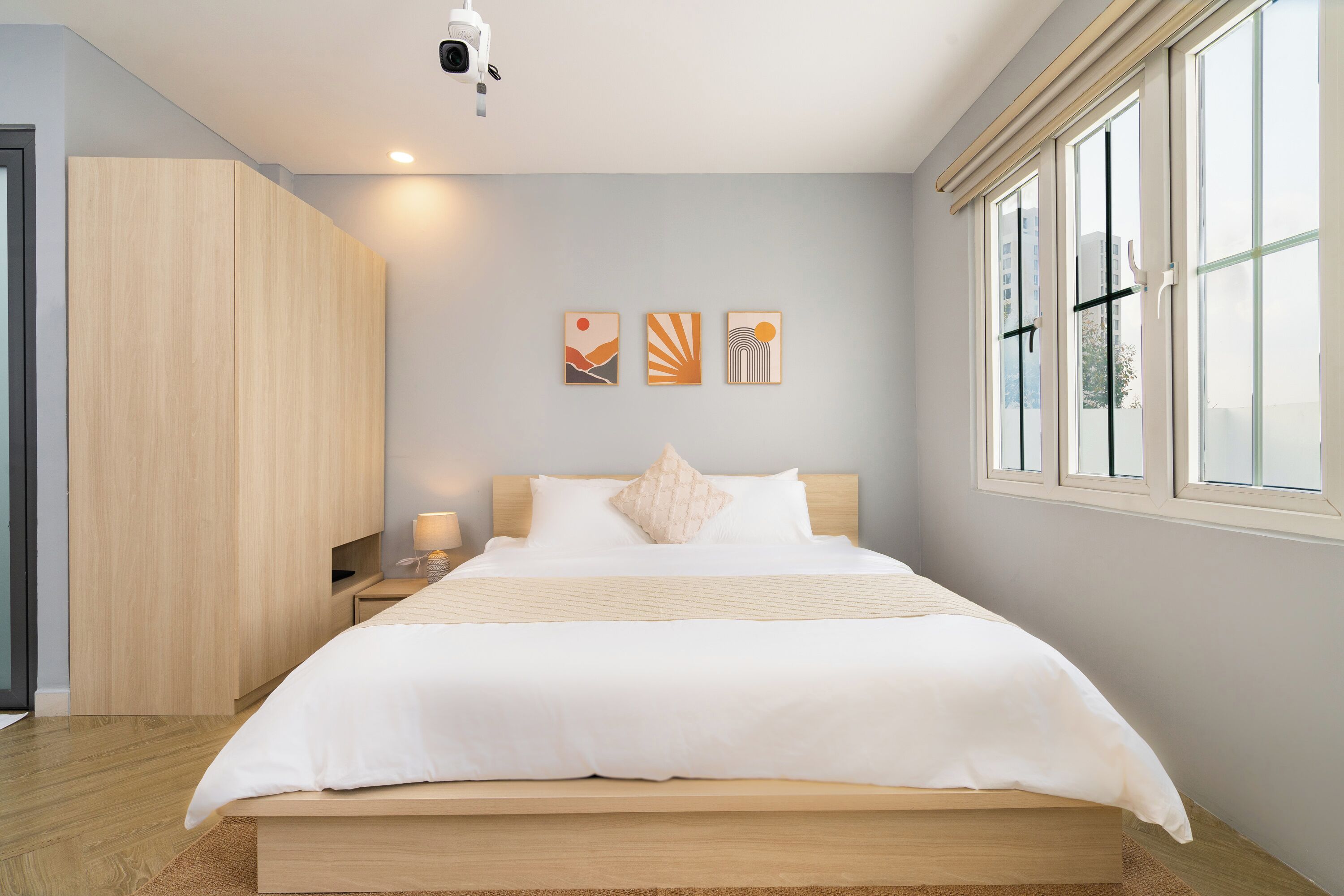 A modern bedroom with a large bed, wooden wardrobe, and artwork on the wall.