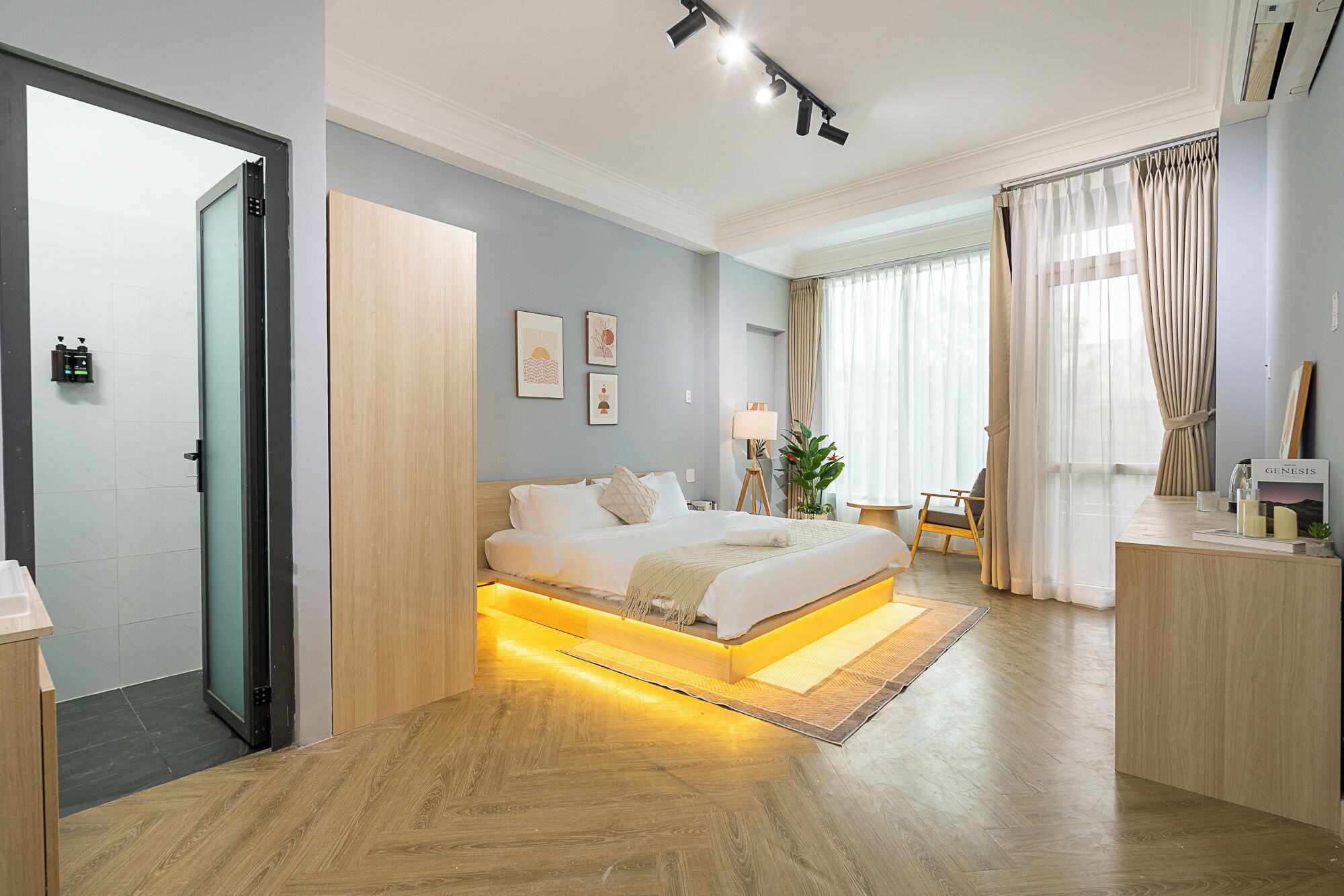 Habitación de hotel moderna con cama, mesita de noche, lámpara y vistas al exterior.
