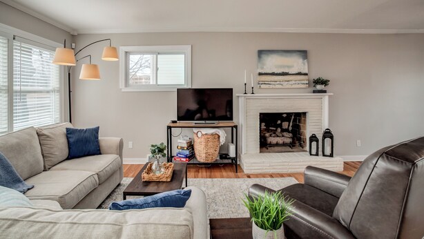 A living room with a sofa, a coffee table, a fireplace, a television, and a large window with blinds. - Family friendly, Youth Sports tournaments, World Cup-Ready, Lenexa, 3BR Near KC (Lenexa)