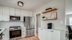 A modern kitchen with white cabinets, stainless steel appliances, and wooden flooring. - Family friendly, Youth Sports tournaments, World Cup-Ready, Lenexa, 3BR Near KC (Lenexa)
