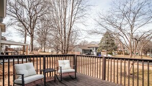 A wooden deck with two rocking chairs and a table, surrounded by a wooden fence. - Family friendly, Youth Sports tournaments, World Cup-Ready, Lenexa, 3BR Near KC (Lenexa)