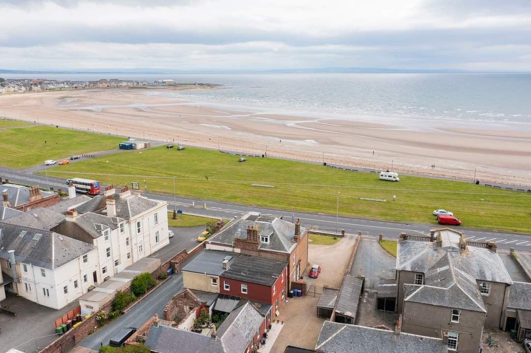 A coastal town with a beach, residential buildings, and a road leading to the beach.