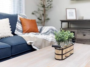 A living room with a sofa, a coffee table, and a decorative plant arrangement. - Bright & Spacious w/ Fast Wi-Fi (Perry)