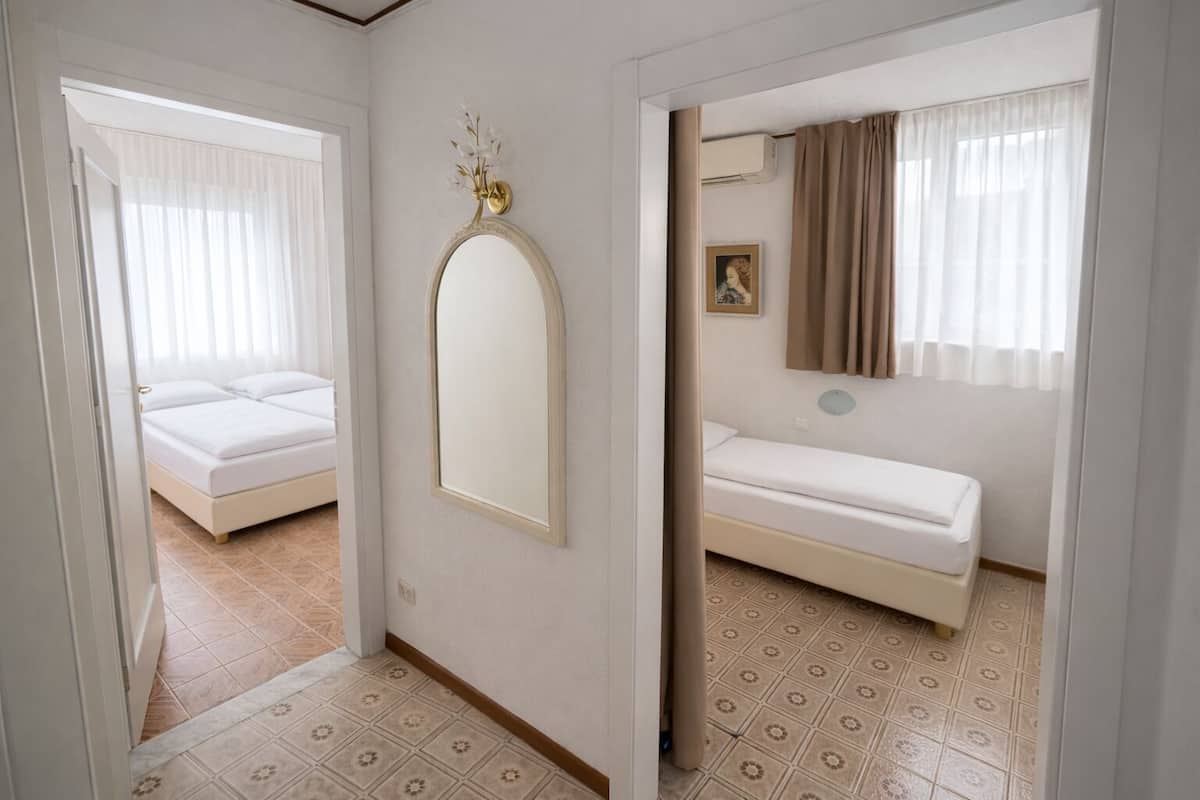 Una habitación con cama, espejo y ventana con cortinas.