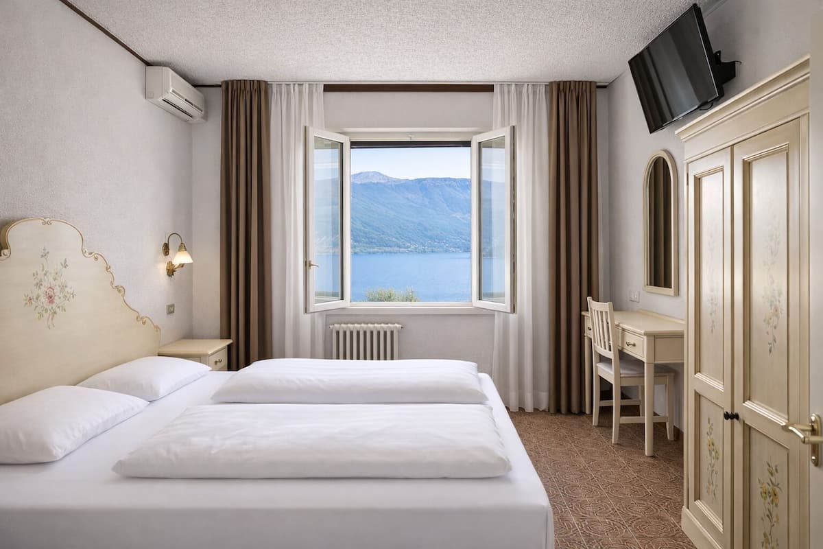 Habitación de hotel con una cama grande, un escritorio, una silla, un televisor y una ventana con vista a la montaña.