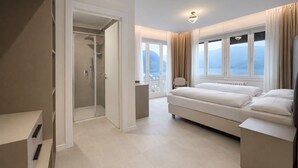 Une chambre d’hôtel moderne dotée d’un grand lit, d’un dressing, d’une douche et d’un balcon avec vue.