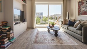 Moderni olohuone, jossa on litteänäyttöinen televisio, kirjahylly, sohvapöytä ja sohva.