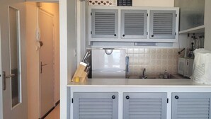 Een kleine keuken met een ingebouwde oven, een spoelbak en een klein aanrecht.