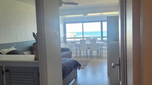 Een hotelkamer met een bed, een bureau en uitzicht op zee.