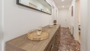 Ein modernes Badezimmer mit einem Holzbadezimmerunterschrank, einer runden gewebten Ablage, einem Spiegel und einem weißen Waschbecken.