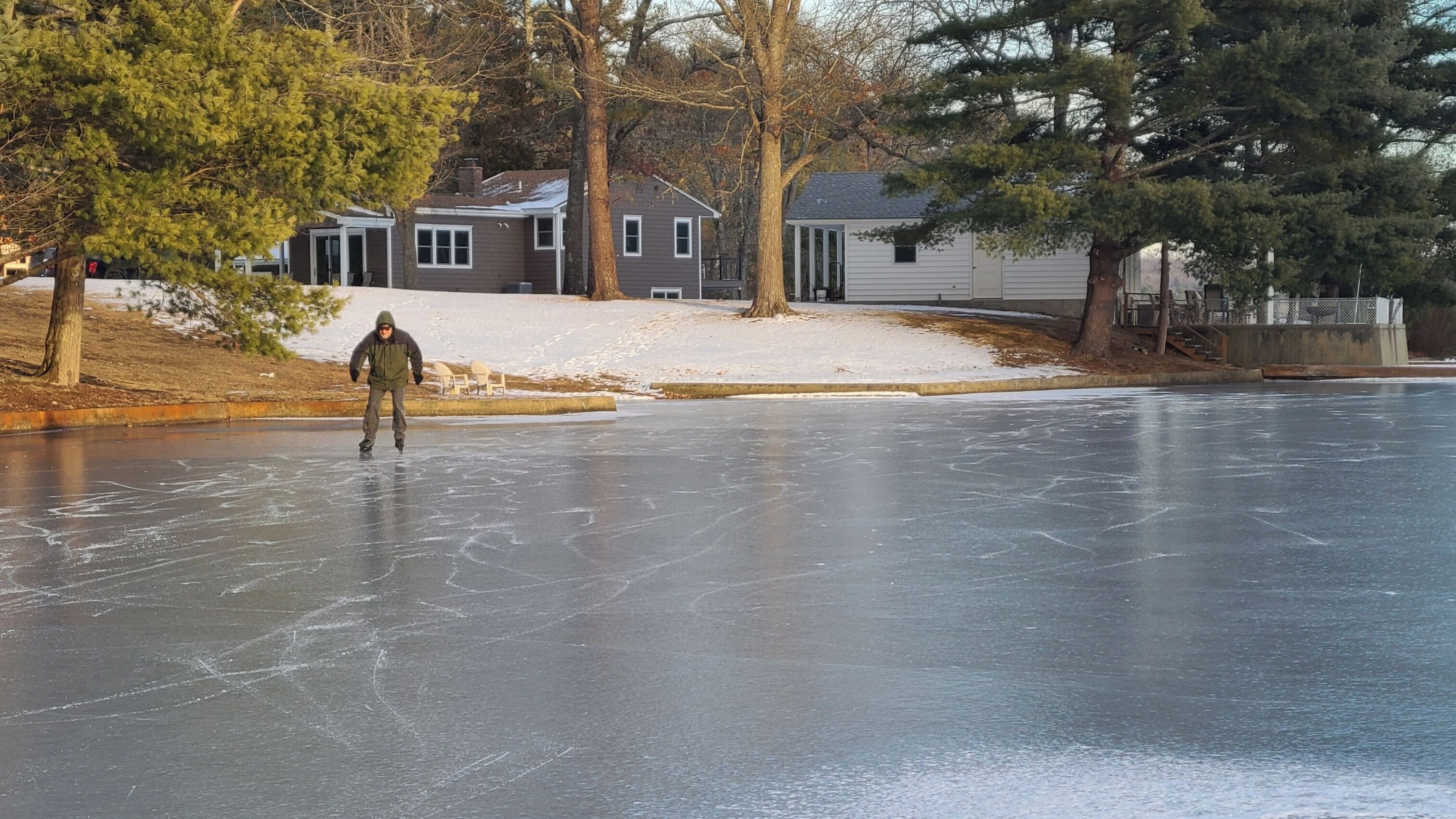 A person ice skating on a frozen surface with houses in the background.