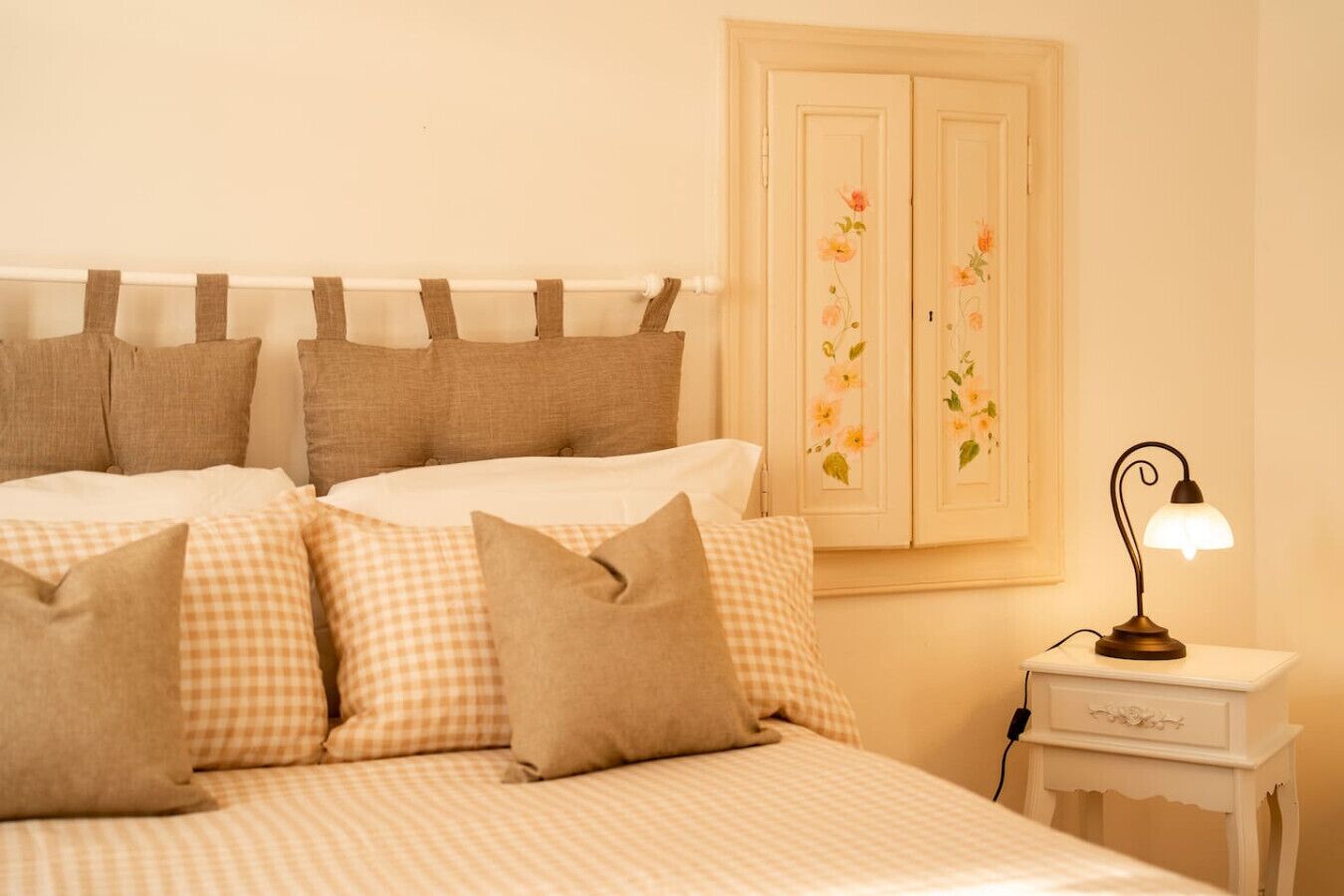 A bedroom with a bed, pillows, a nightstand, and a lamp.