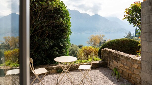 Eine Terrasse mit Tisch und zwei Stühlen mit Blick auf eine gebirgige Landschaft.