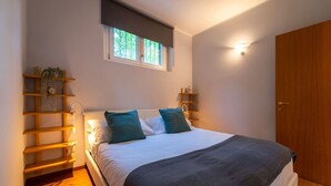 Ein Schlafzimmer mit einem Bett, zwei Nachttischen, einem Fenster und einer Tür.
